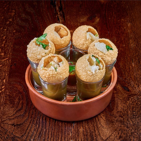 Pani Puri, crispy Indian street food, served in shot glasses with flavorful liquid and fillings.